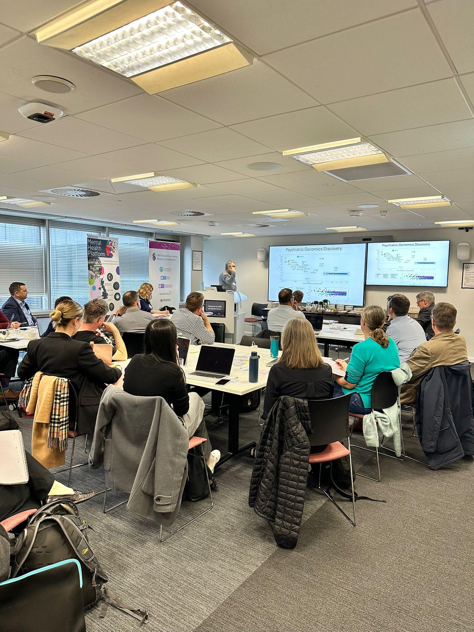 Researchers sitting at tables watching presentation