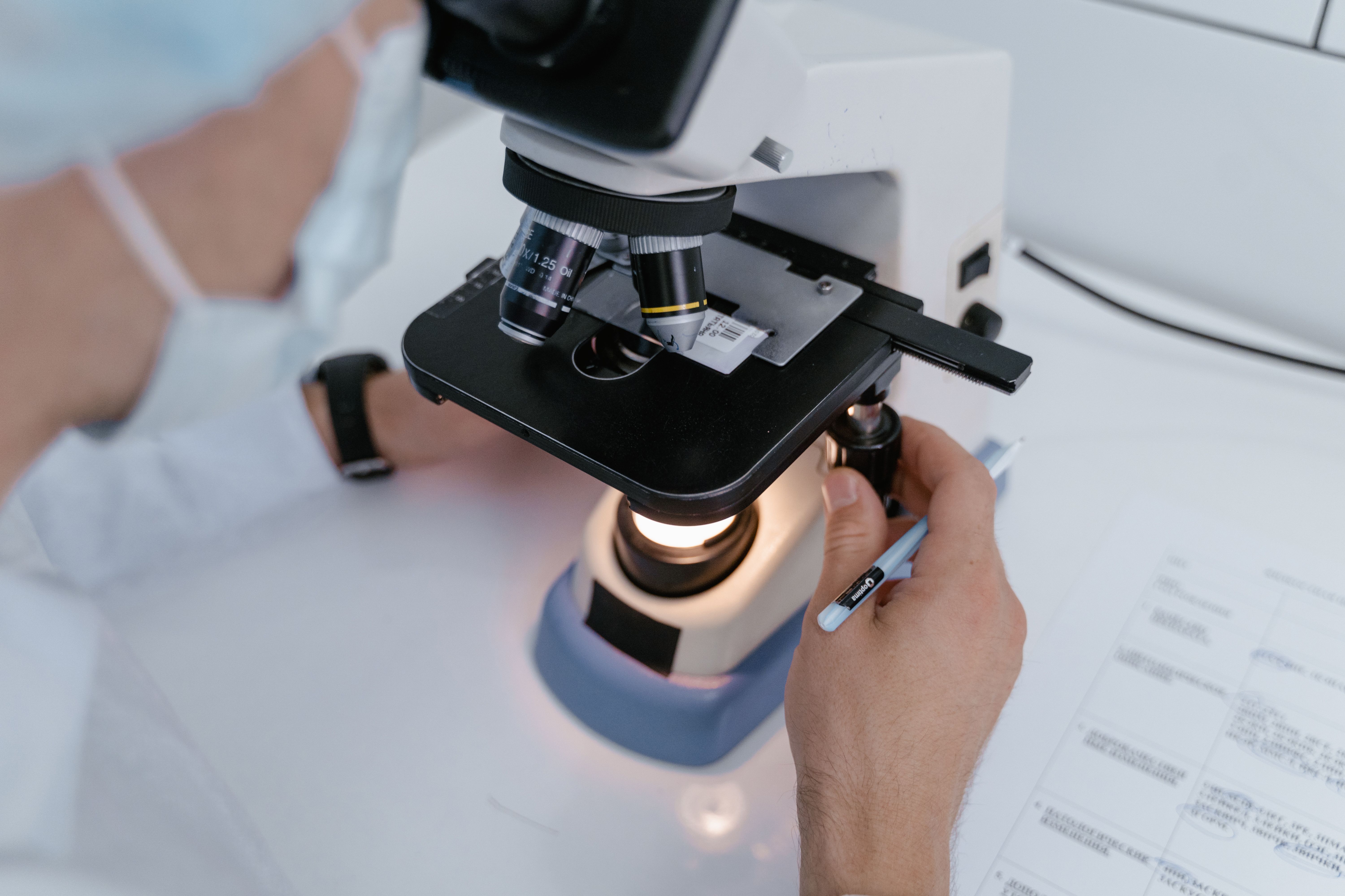 researcher looking down microscope