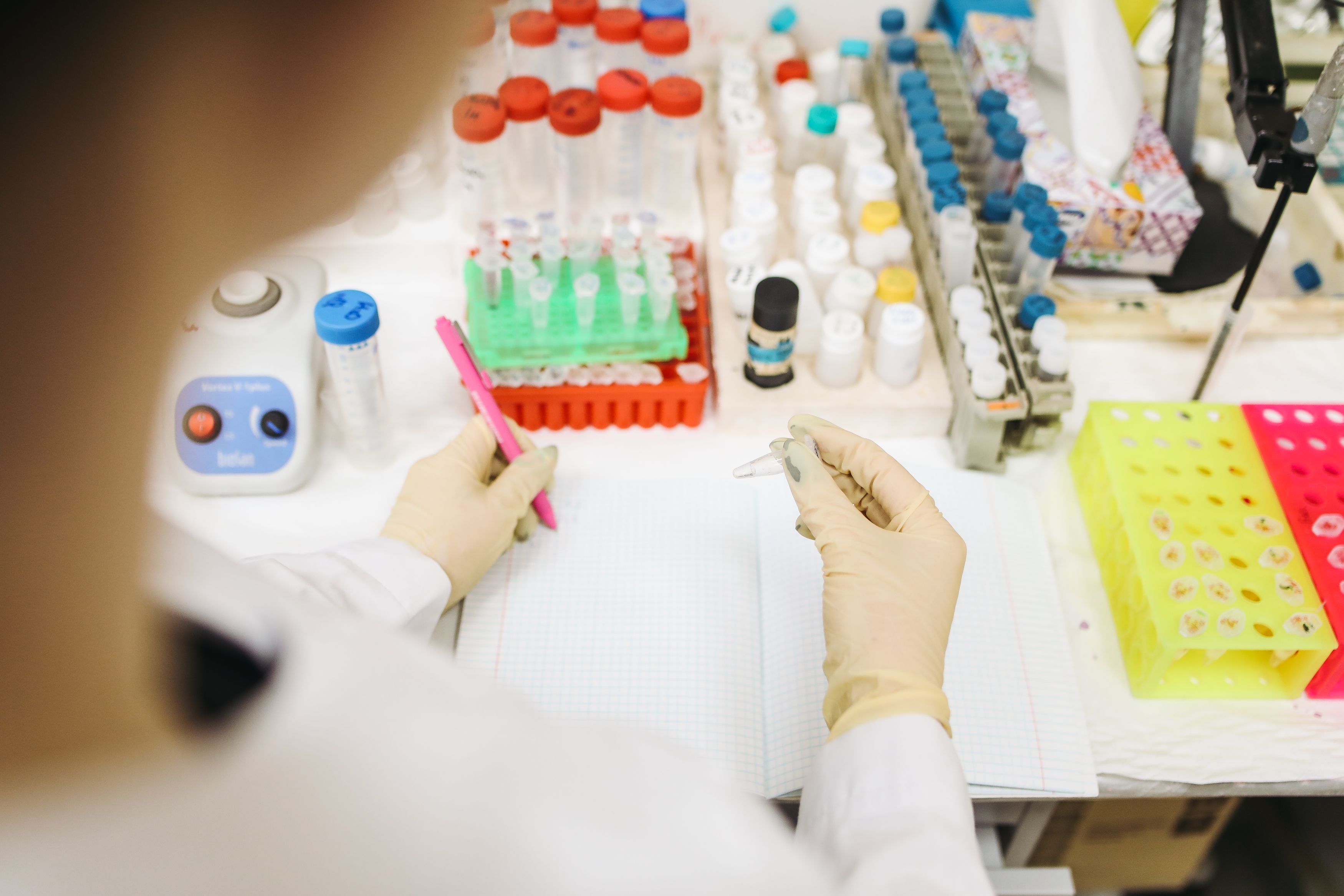 lab bench with gloved hands and tubes 