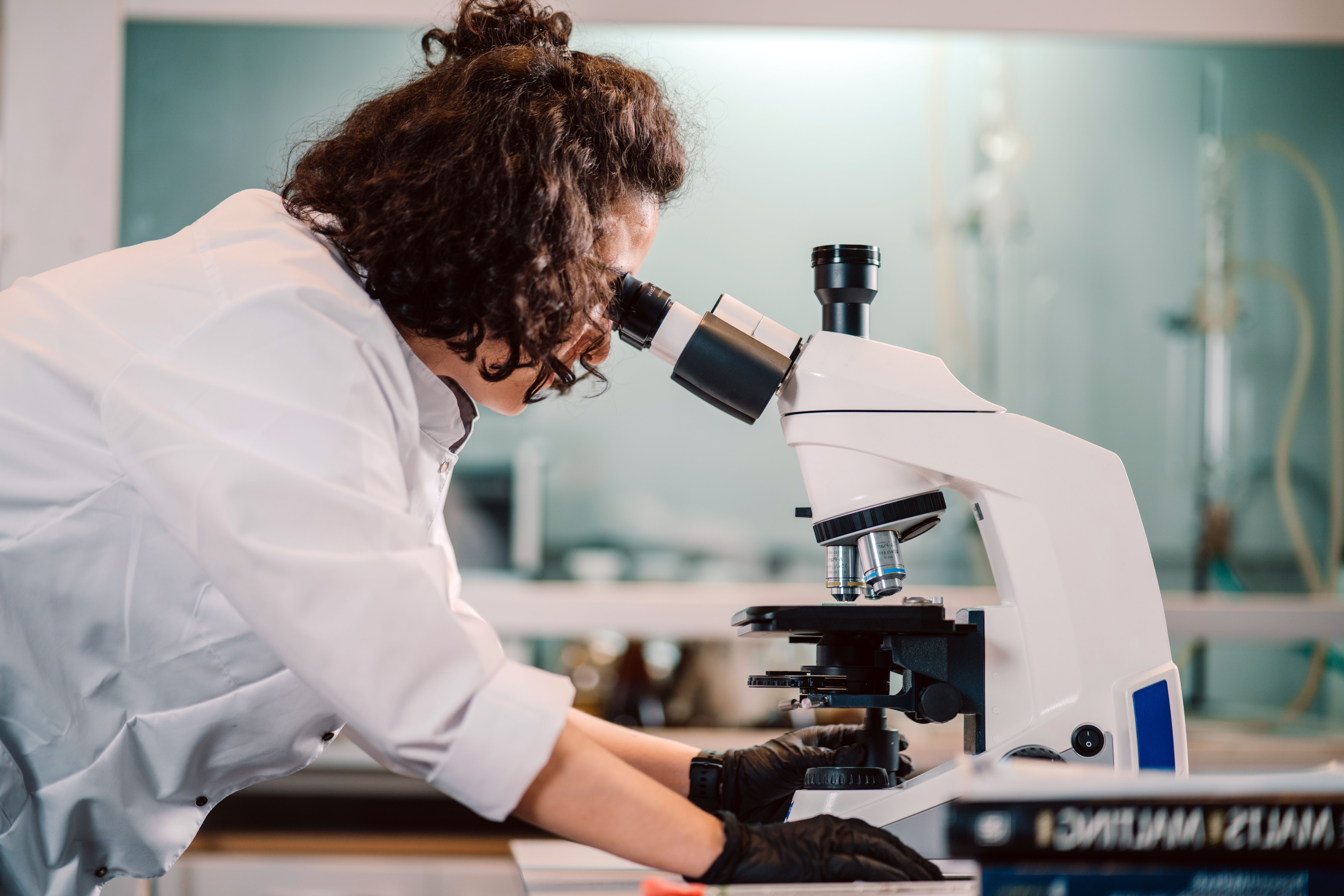 researcher looking through microscope 